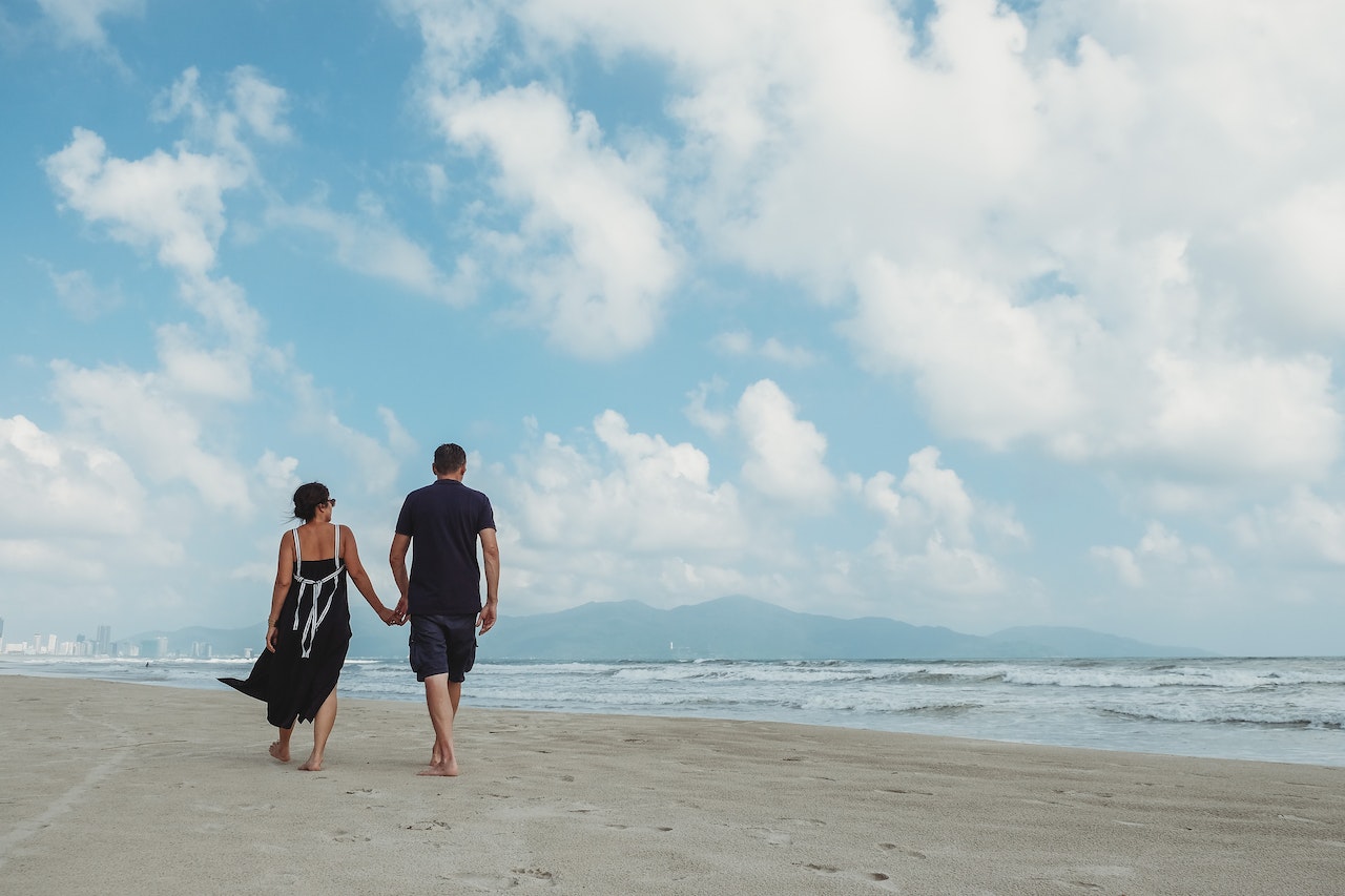 Couple Walking At The Beach While Holding Hands