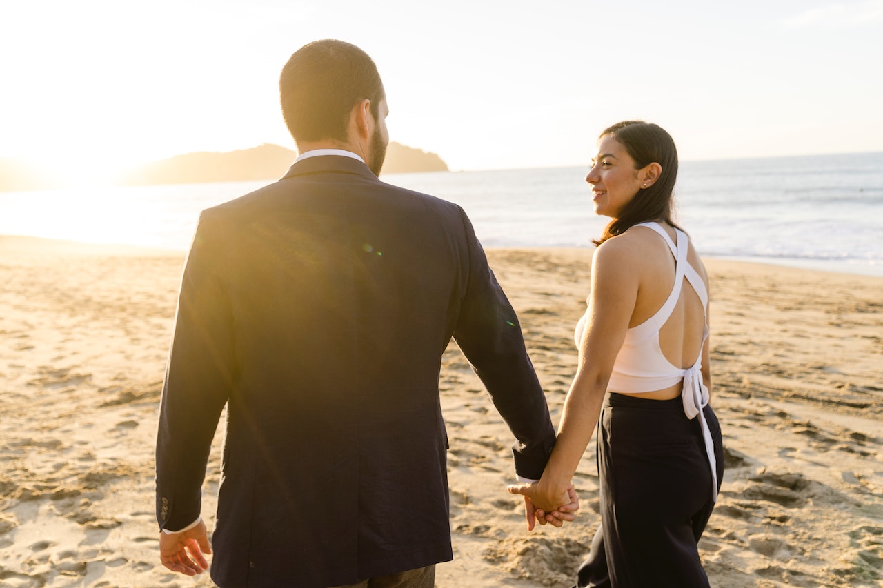 Man and Woman Holding Hands While Walking on Beach
