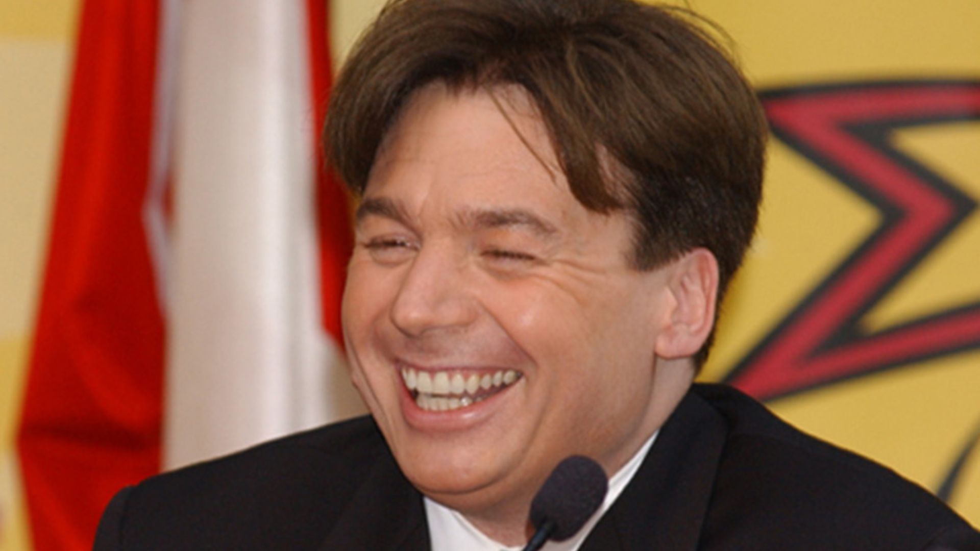Mike Myers Laughing In Front Of A Mic