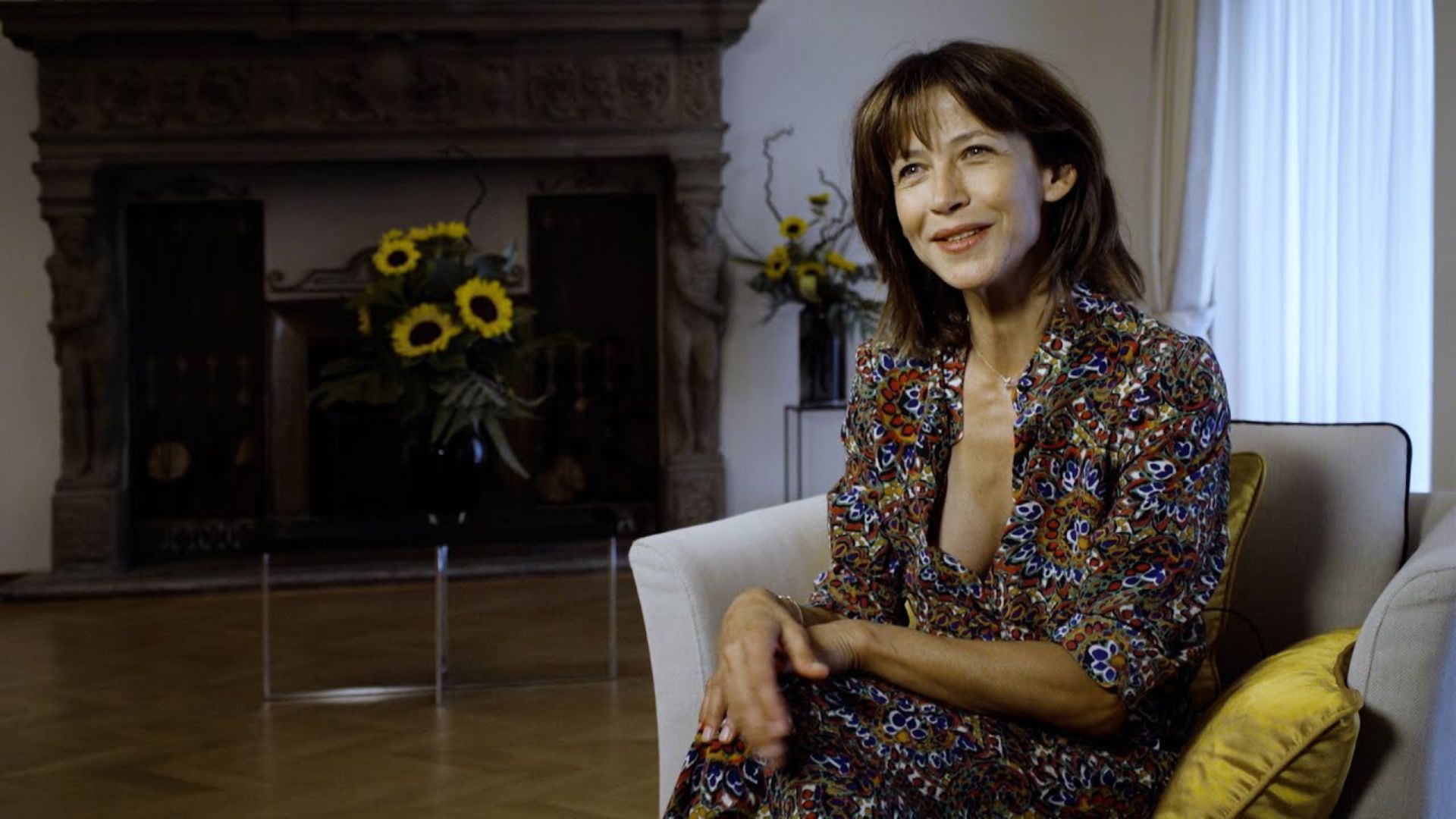 Sophie Marceau Sitting On Sofa And Smiling