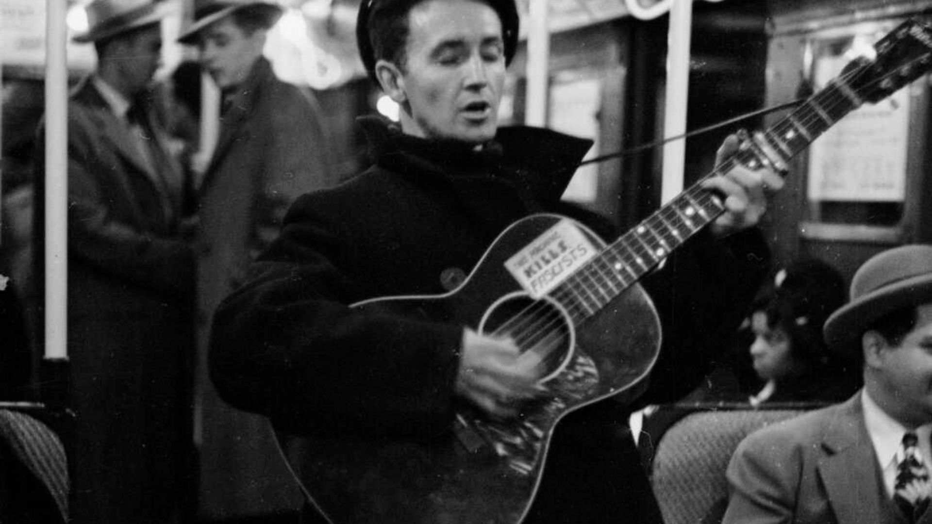 Woody Guthrie Performing With His Guitar On A Train