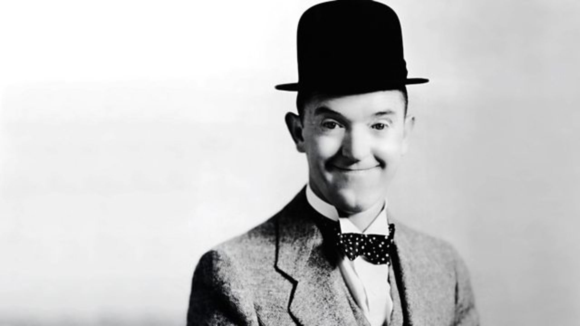 Stan Laurel Wearing A Black Hat And Smiling