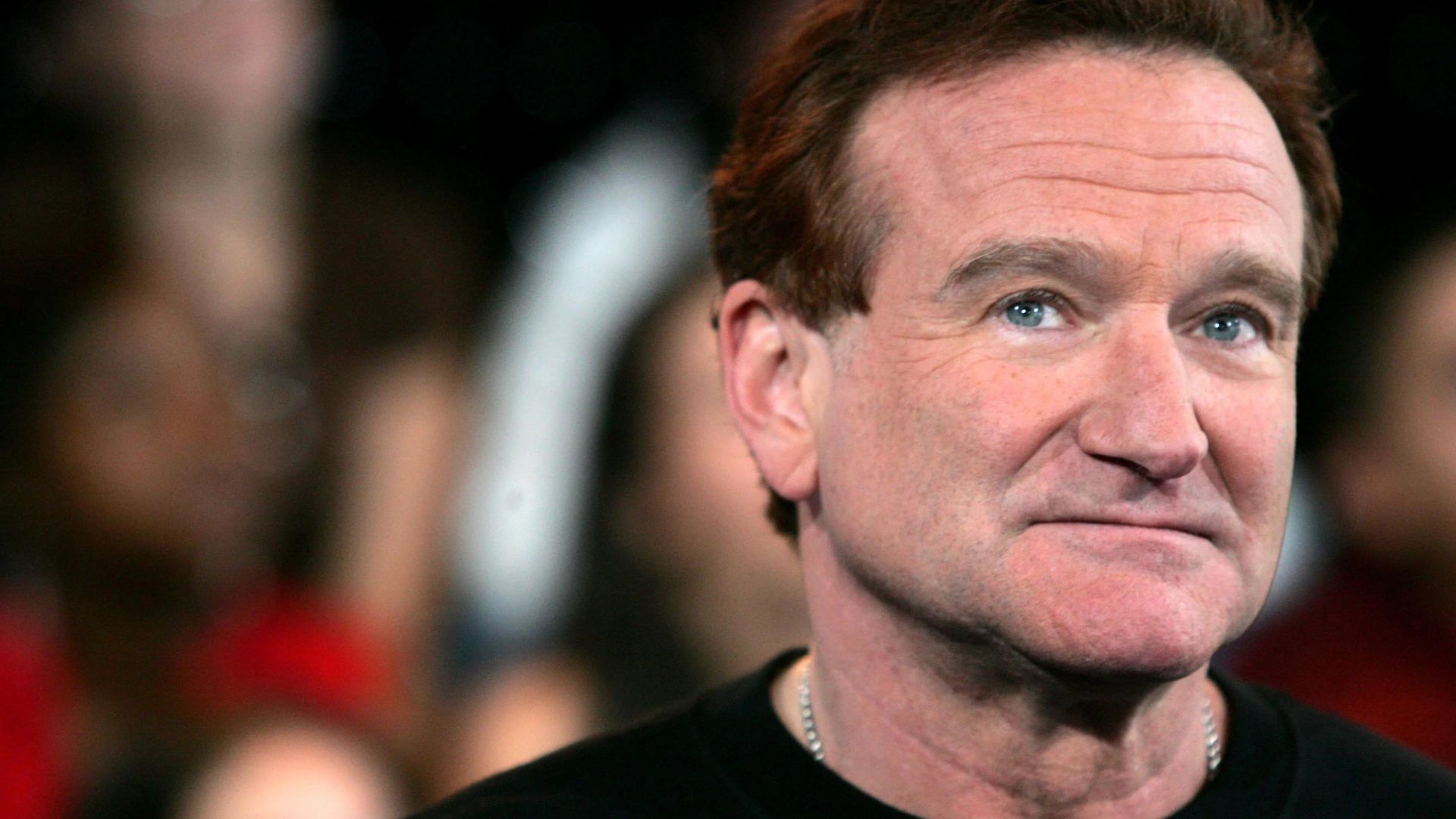 Robin Williams Wearing A Black Shirt And Silver Necklace