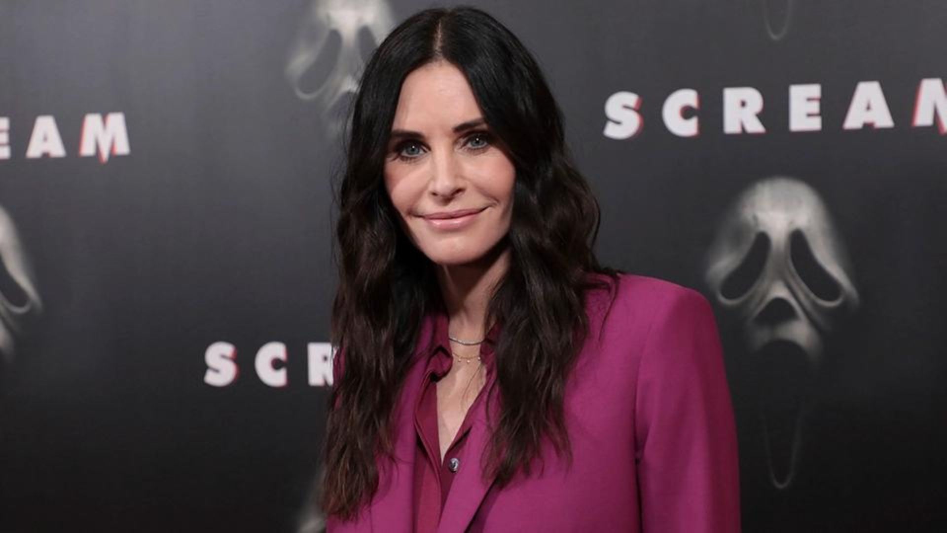 Courteney Cox Smiling And Black Poster On Background