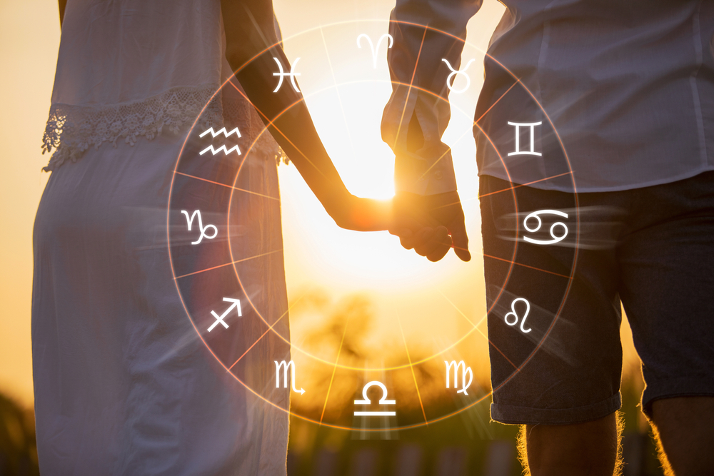 A couple holding hands with a zodiac wheel between them.