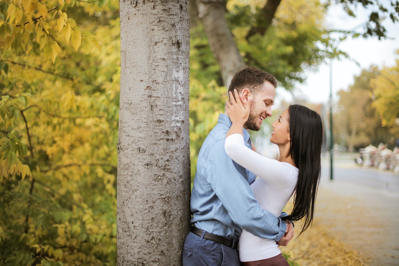 Couple Hugging while Leaning on a Tree