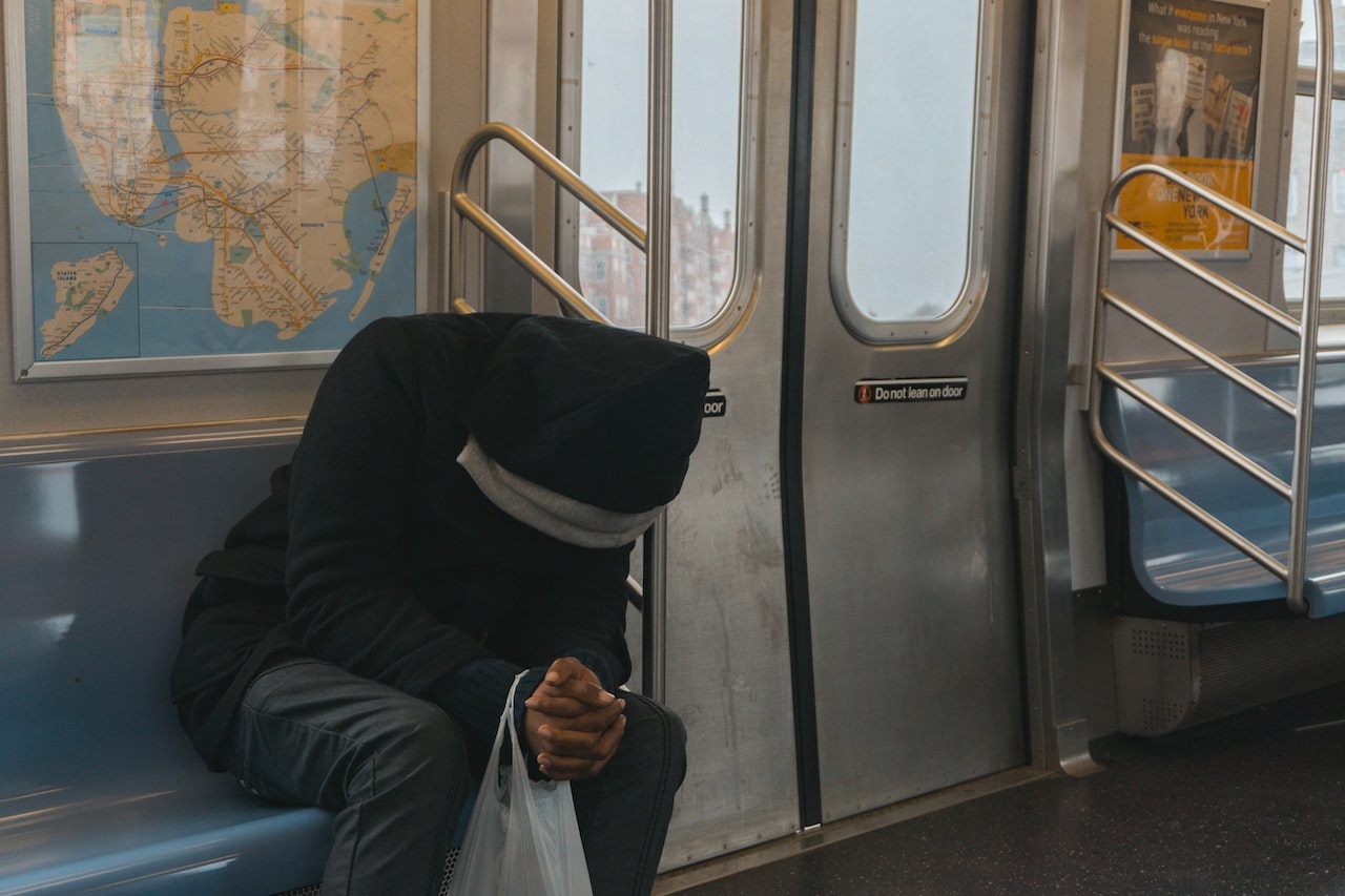 Person in Black Hoodie Sitting on a Train Bench