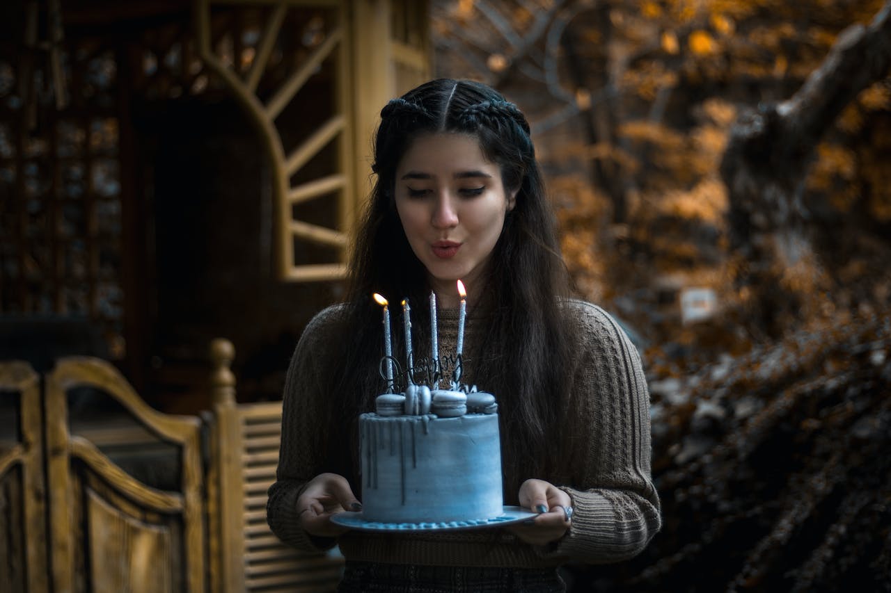 Woman Wearing a Sweater Holding a Birthday Cake