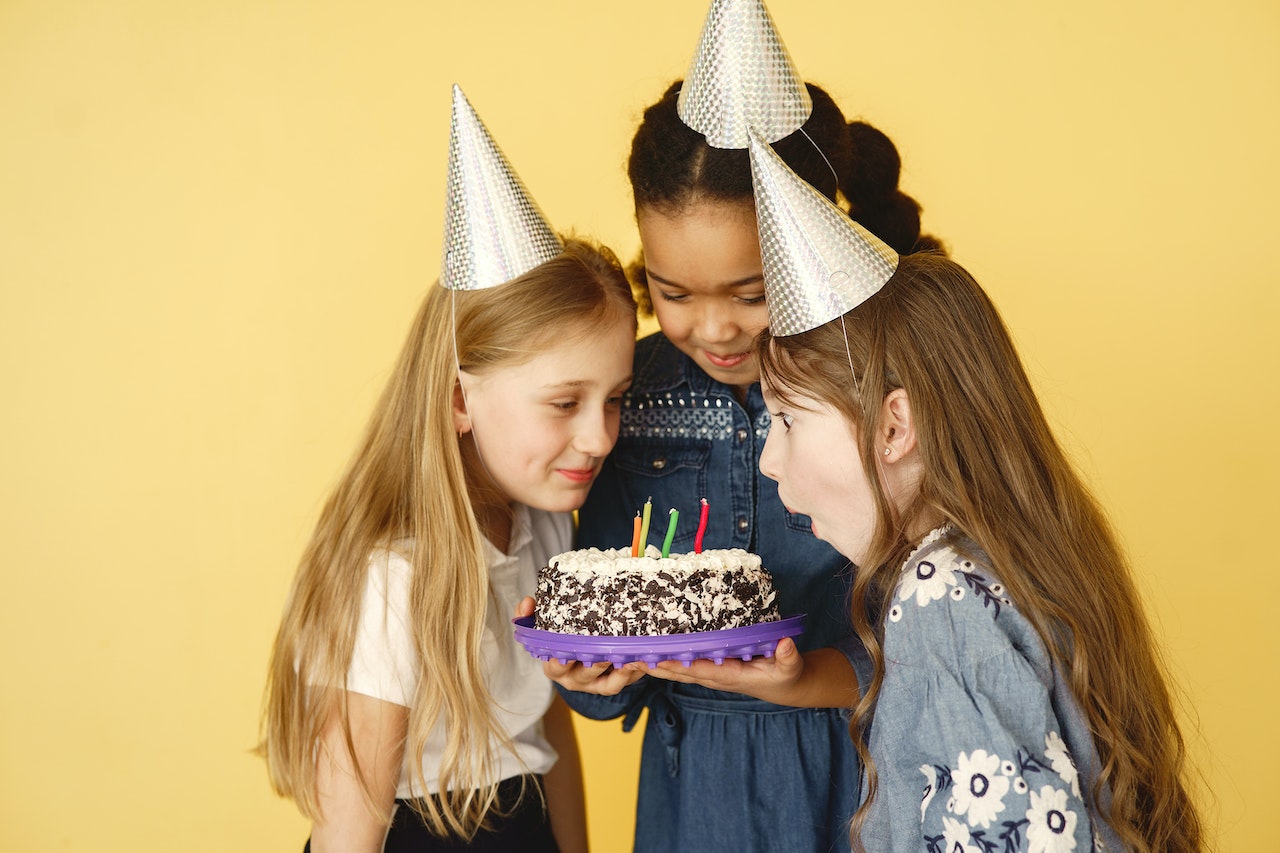 Kids Wearing Party Hats in Front of a Cake with Candles