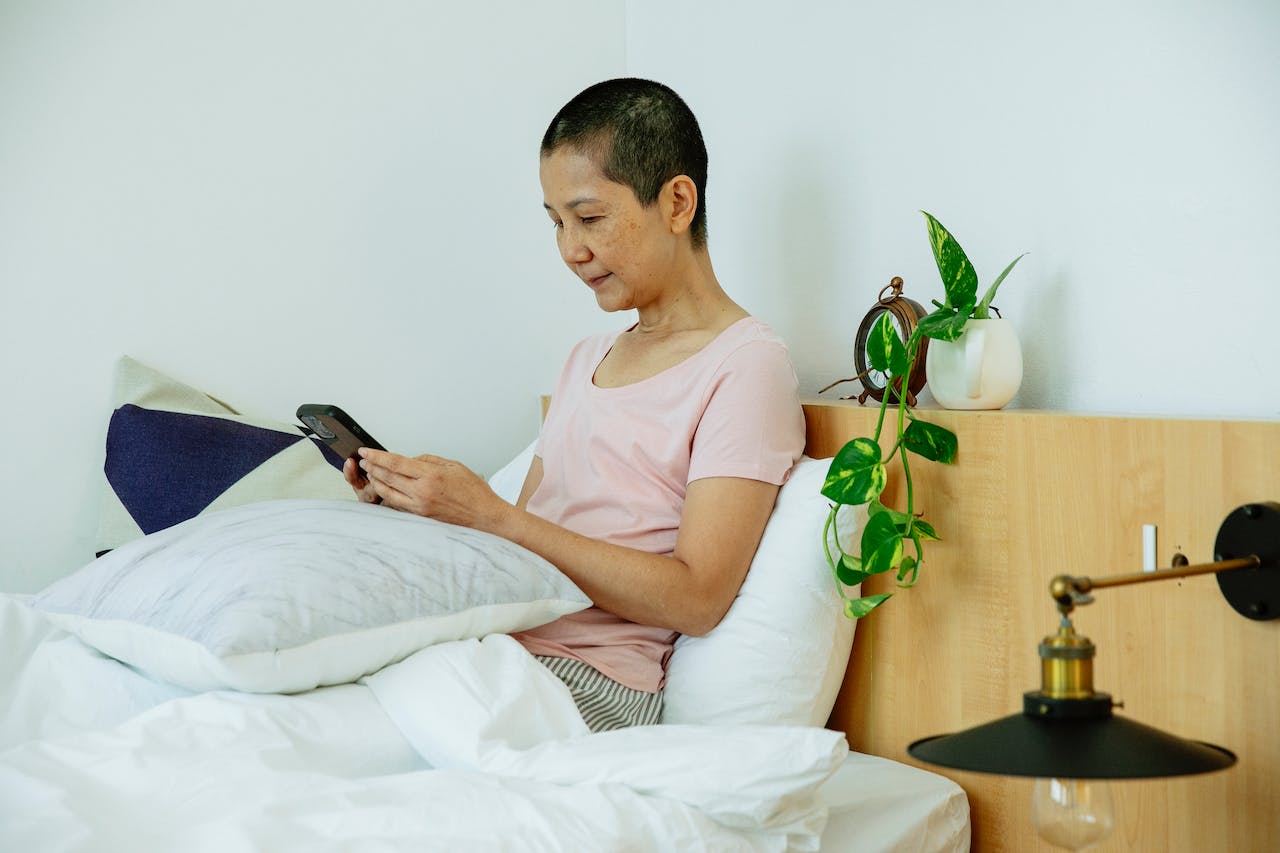 Serious Asian Female Scrolling on Phone in Bed