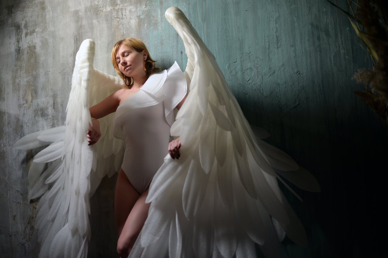 Dreamy Woman With Fluffy Angel Wings Against Rough Wall