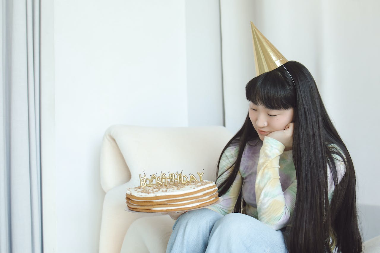 Woman Sitting on White Sofa Chair Holding a Cake