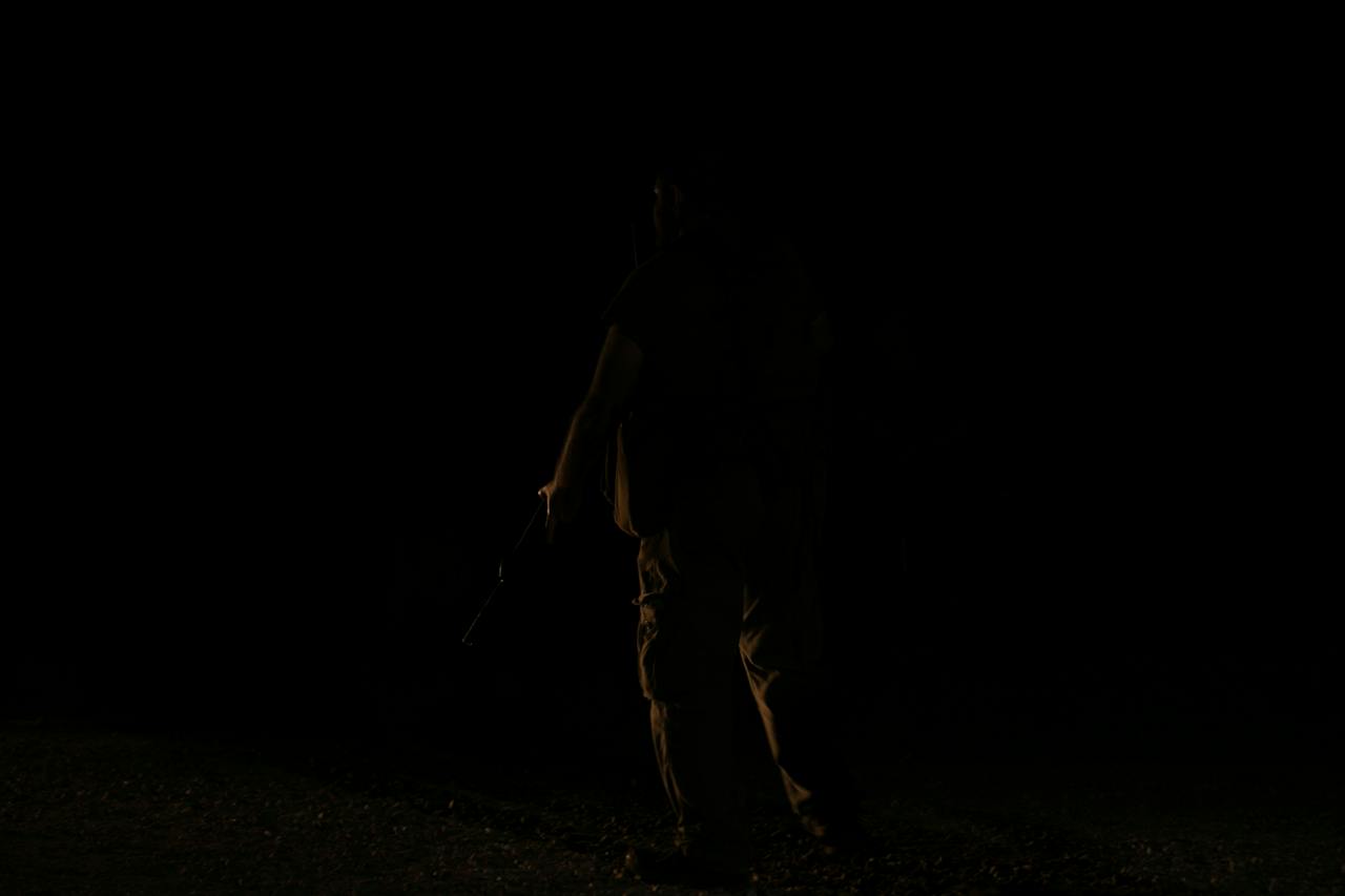 Unrecognizable person in darkness on black background