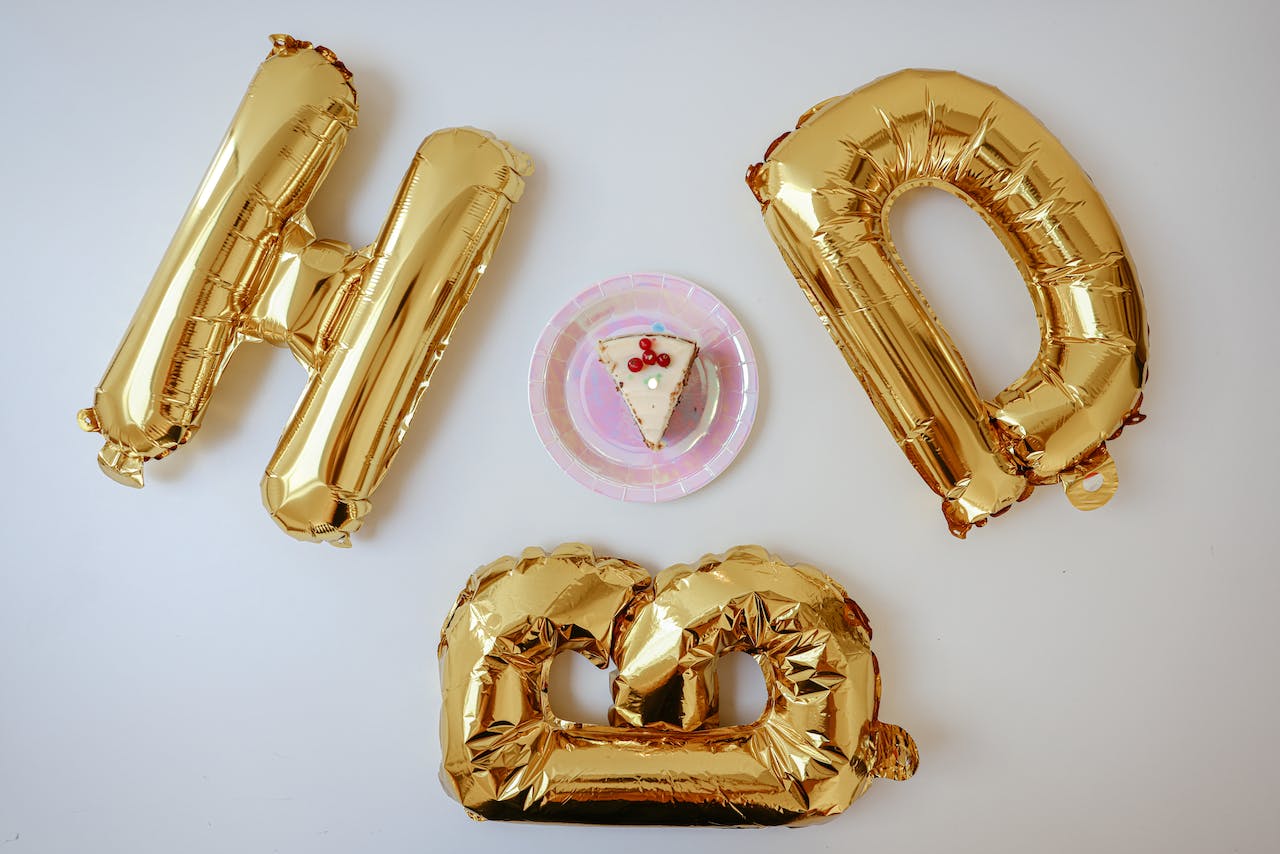 Slice Of Cake Beside Gold Balloons