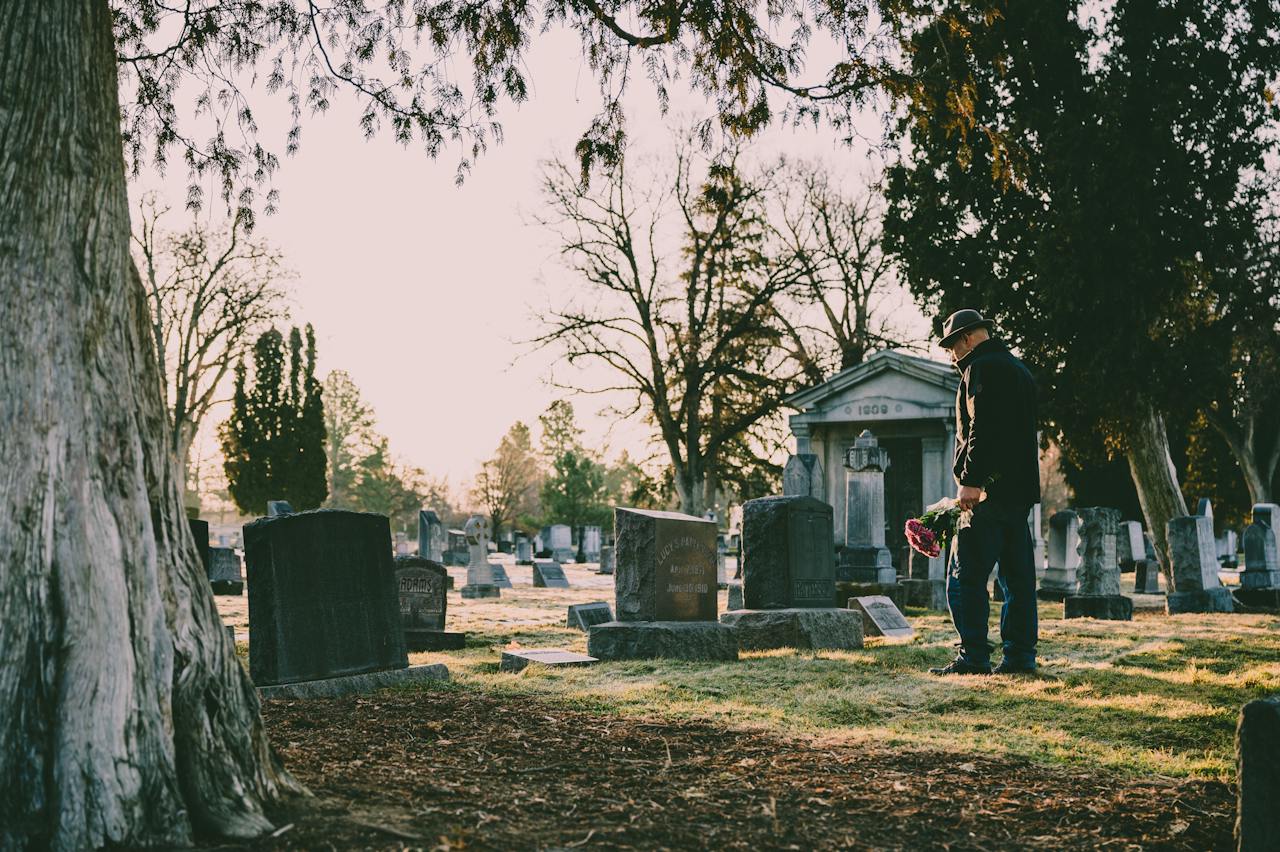 Man in Black Jacket Standing in Front of Grave