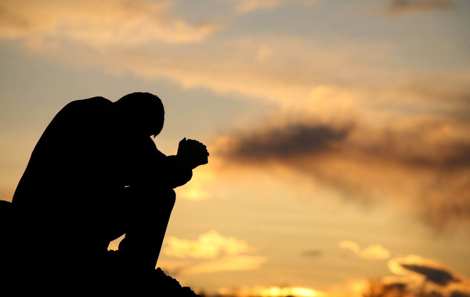 A Man Sitting On Rock And Praying