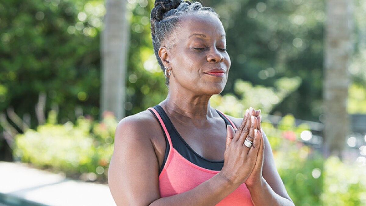 A woman meditating with her hands together in a prayer pose