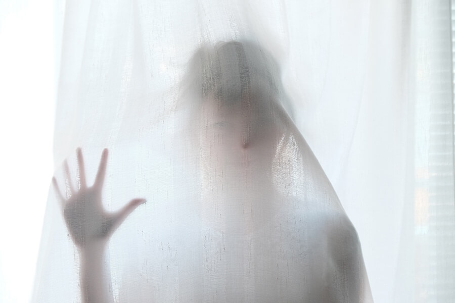 A woman at the back of a white curtain.