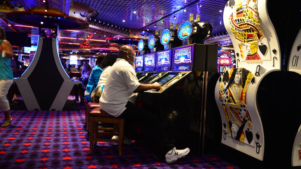 People playing on gambling machines in casino.