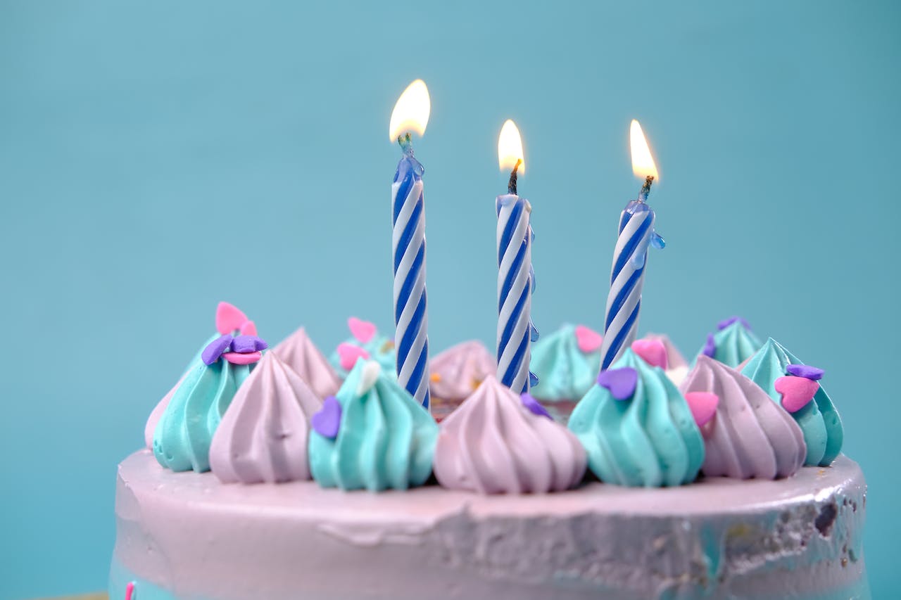 3 Lit Candles on a Blue and Pink Cake