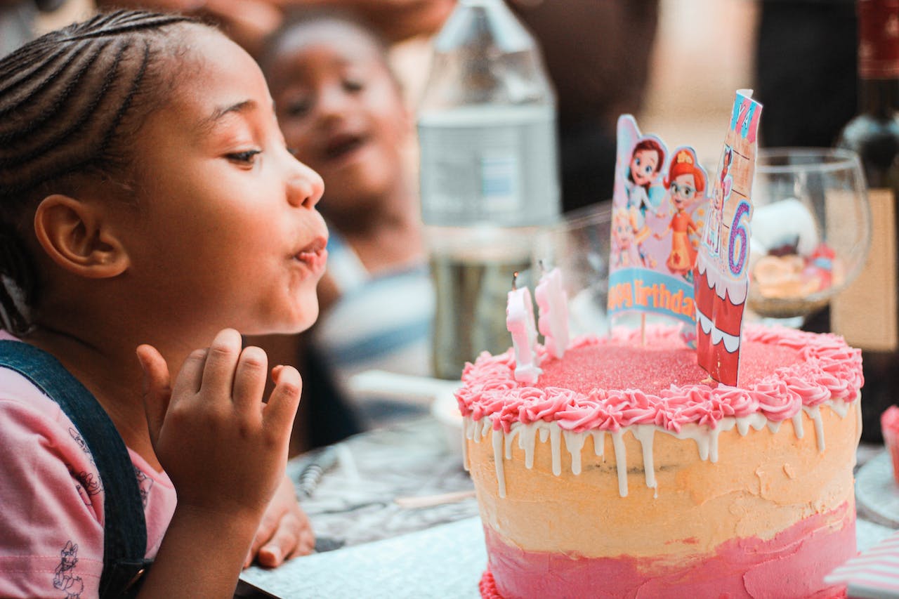 Happy Child Blowing out Candles During Birthday Celebration