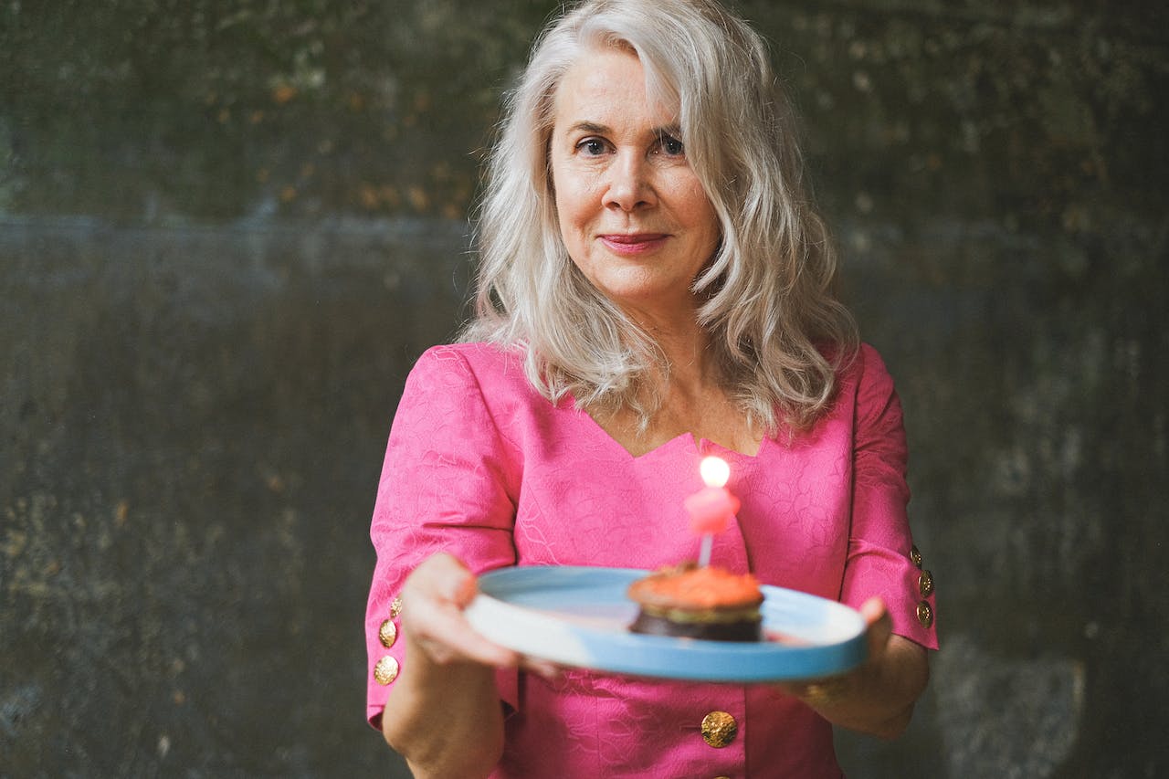 Woman with Gray Hair Holding a Plate with a Birthday Cake